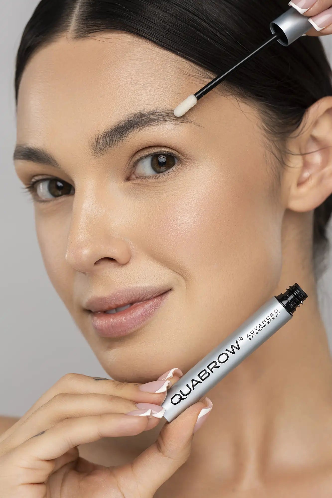 Femme brune appliquant le sérum avancé pour sourcils QUABROW sur la zone des sourcils, gros plan sur l&