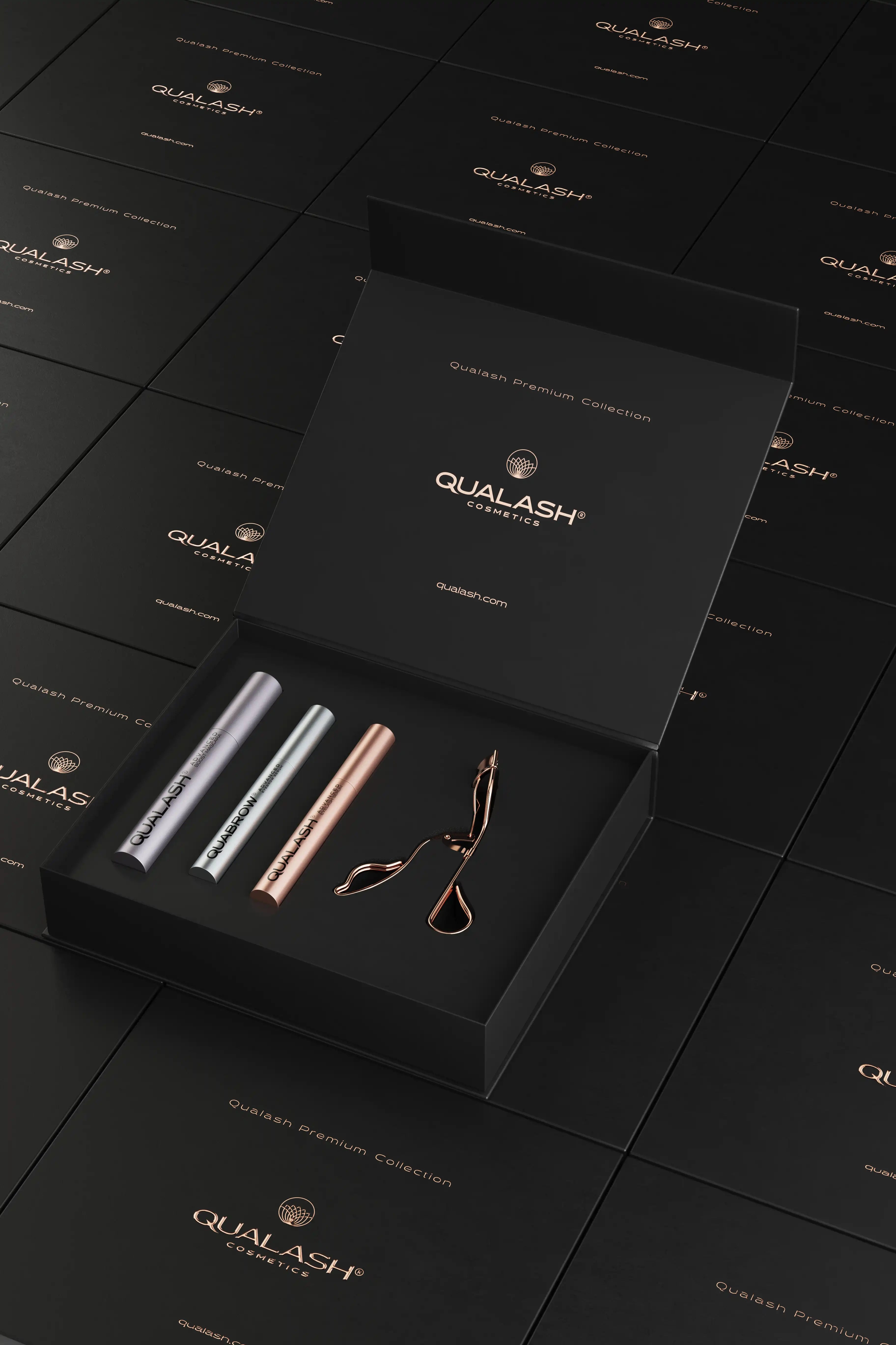 Mise en scène artistique d’un coffret ouvert Qualash Premium Collection avec boîtes flottantes et recourbe-cils