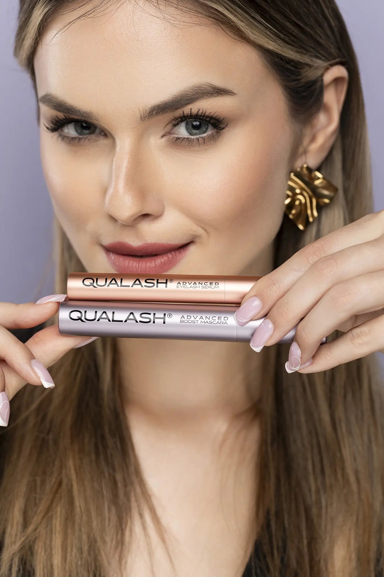Nærbillede af hænder, der holder QUALASH Advanced Eyelash Serum og Mascara Volume Max