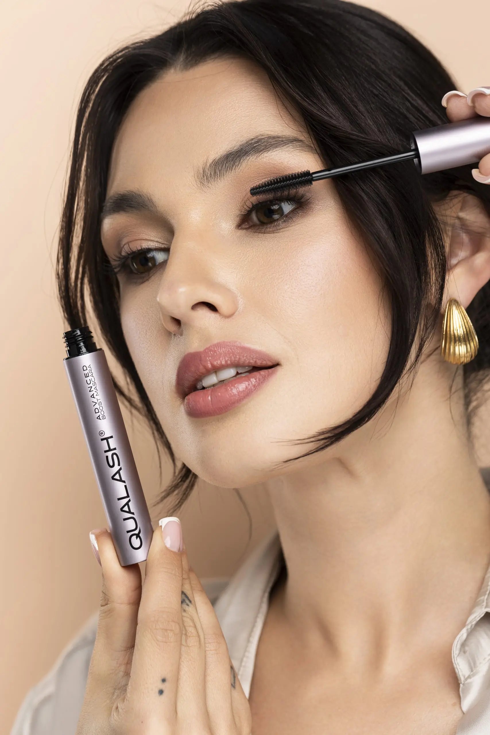 Smilende kvinde holder QUALASH Advanced Mascara Volume Max efter påføring – Trin 2